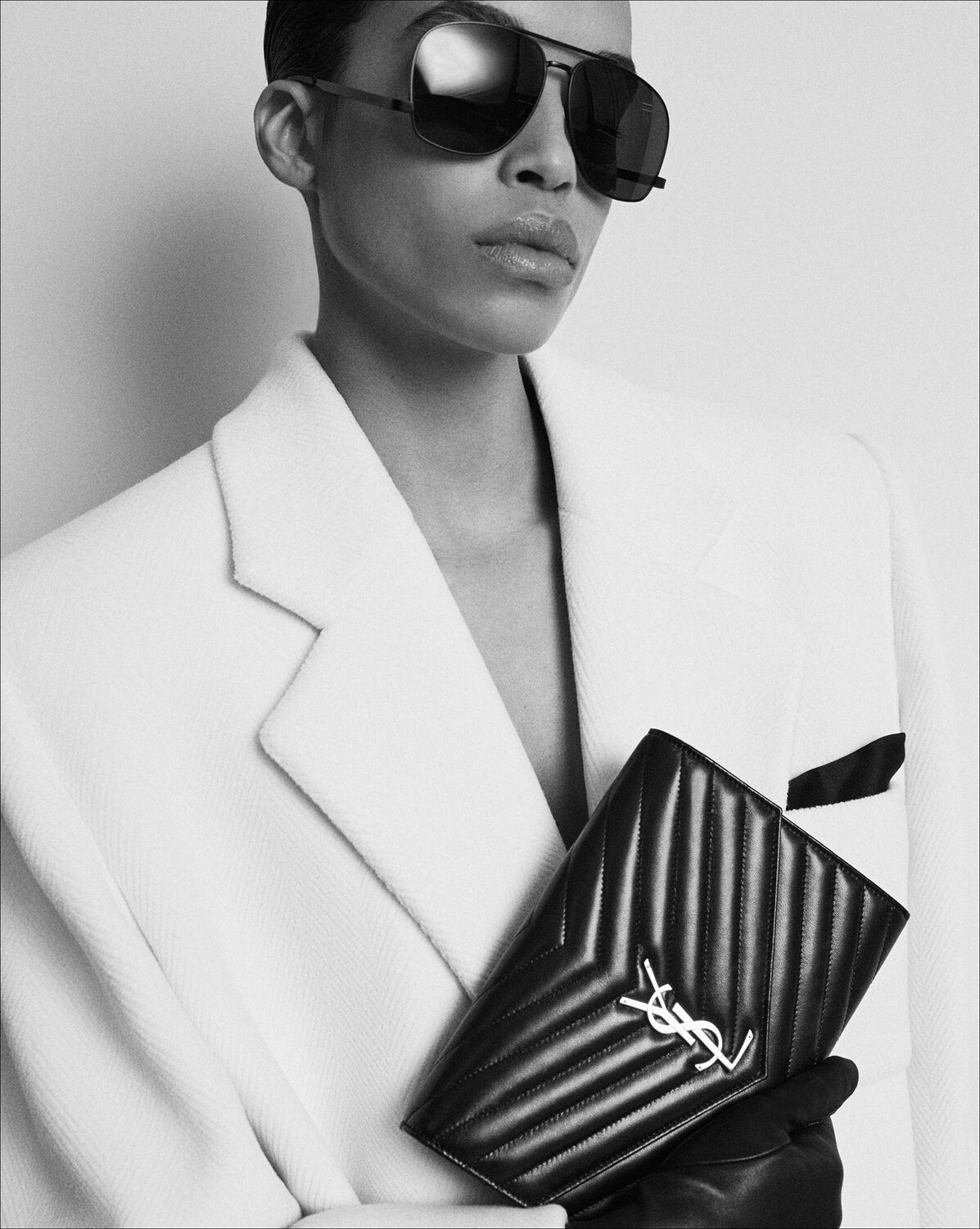 Black Saint Laurent Cassandre Clutch with gold YSL hardware in an editorial setting.